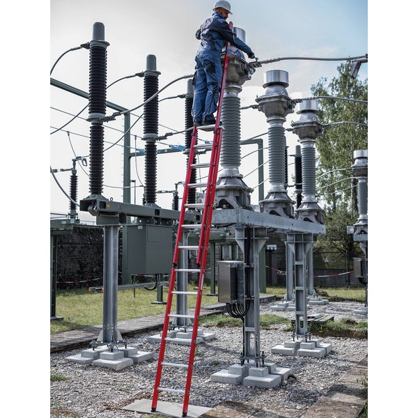 Eine Person auf einer Leiter führt Wartungsarbeiten an einer Hochspannungsanlage durch.