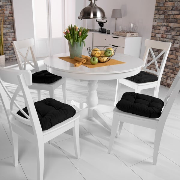 Esszimmer mit weißem Esstisch, Stühlen und schwarzen Sitzkissen.