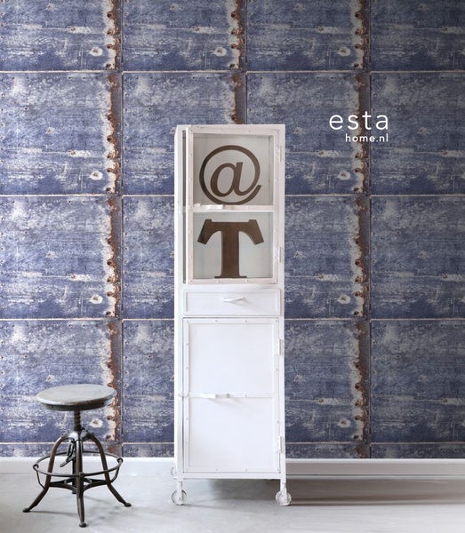 Dekoratives Zimmer mit einer blauen Wandtapete, einem weißen Schrank und einem Hocker