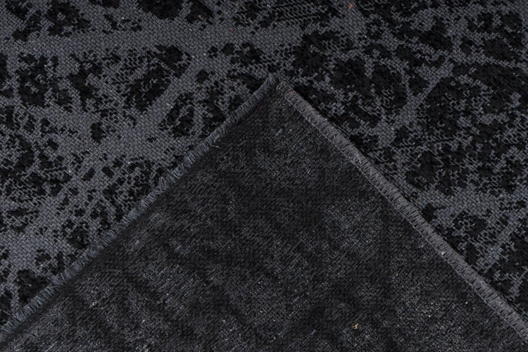 Nahaufnahme eines Teppichs mit abstraktem Muster und umgeschlagener Ecke zur Ansicht der Rückseite.