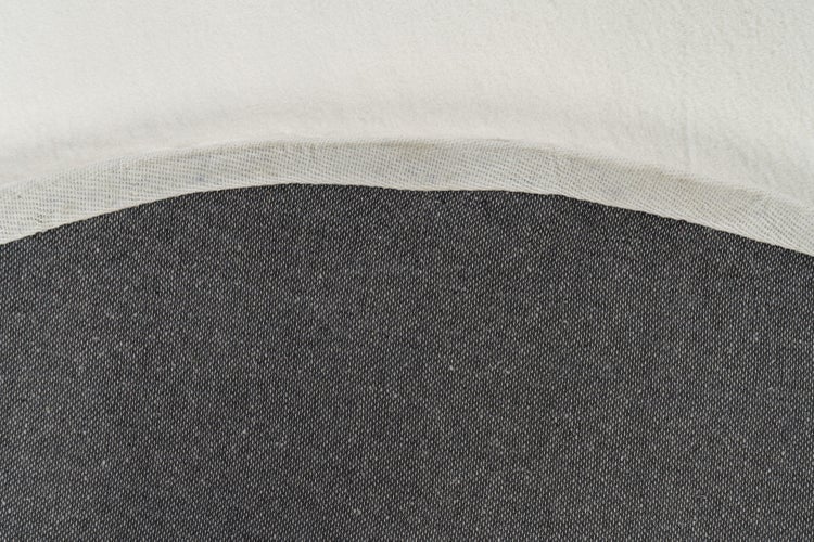 Detailaufnahme von Textilmaterial aus zwei verschiedenen Stoffarten mit einer gebogenen Nahtkante