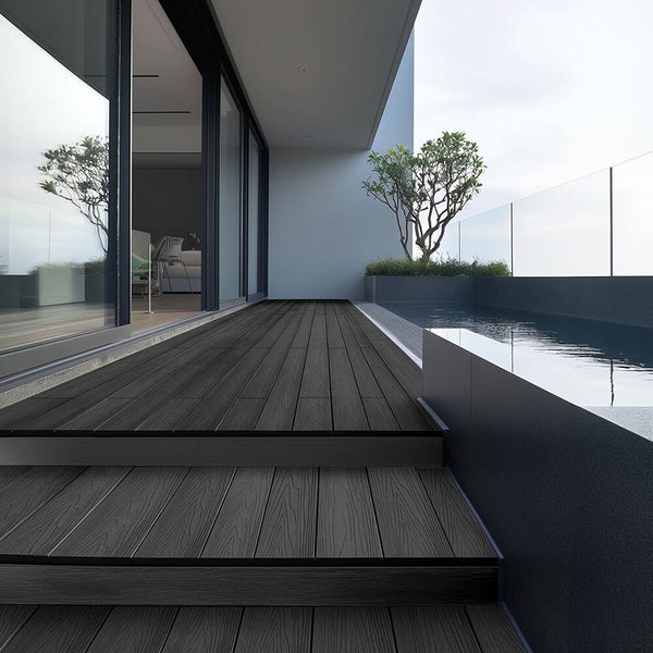 Moderne Terrasse mit dunklen Terrassendielen aus Holz, angrenzendem Pool und Glasgeländer an einem Wohnhaus.
