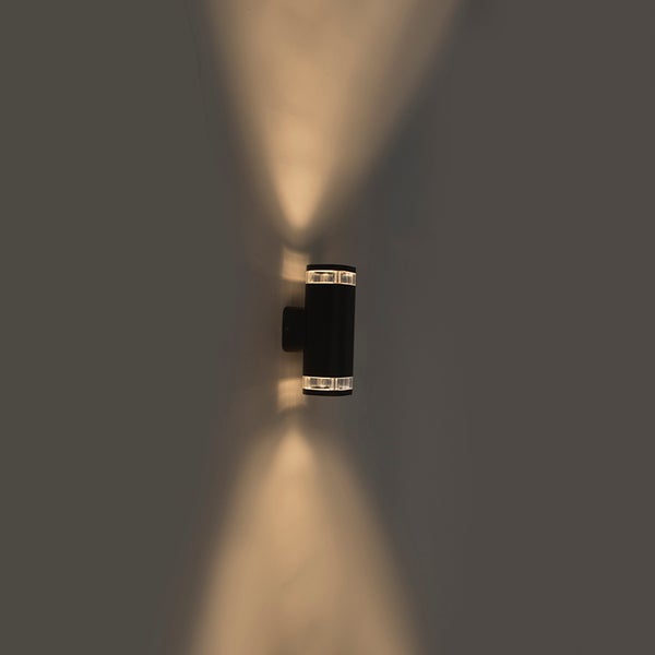 Zylindrische Außenwandleuchte in Schwarz mit Up-and-Down-Lichteffekt an einer Wand montiert.