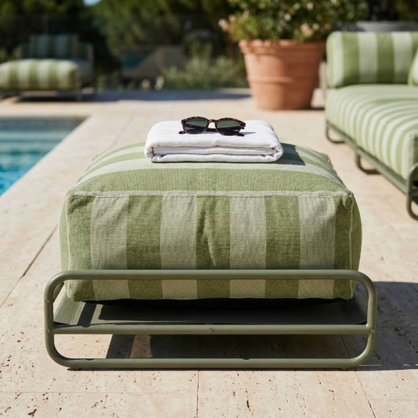 Gestreifter Outdoor-Hocker mit Metallgestell auf einer Poolterrasse, dekoriert mit einem Handtuch und einer Sonnenbrille.