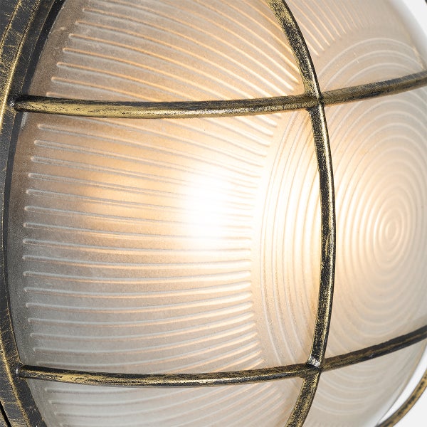 Nahaufnahme einer runden Außenleuchte mit geriffeltem Glas und einem Metallschutzgitter in Antik-Optik, beleuchtet.