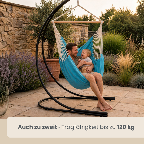 Vater und Kind sitzen in einem Hängesessel mit Metallgestell im Garten auf einer Terrasse.
