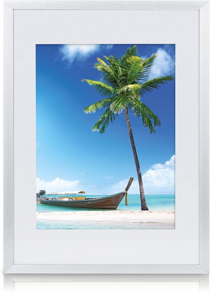 Wandbild im Rahmen mit Motiv von einer Palme und einem Holzboot am Sandstrand vor einem klaren Himmel