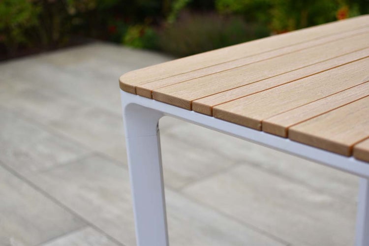 Detailansicht eines Gartentisches mit Holzplatte und weißem Metallgestell