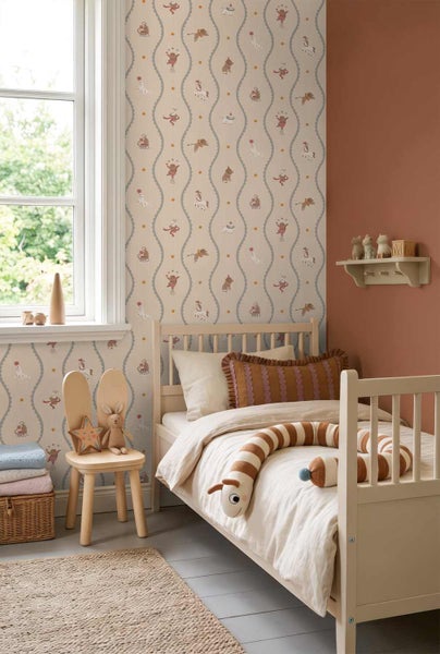 Helles Kinderzimmer mit gemusterter Zirkustapete, einem Kinderbett aus Holz, einem Hasenohr-Stuhl und einem Jute-Teppich.