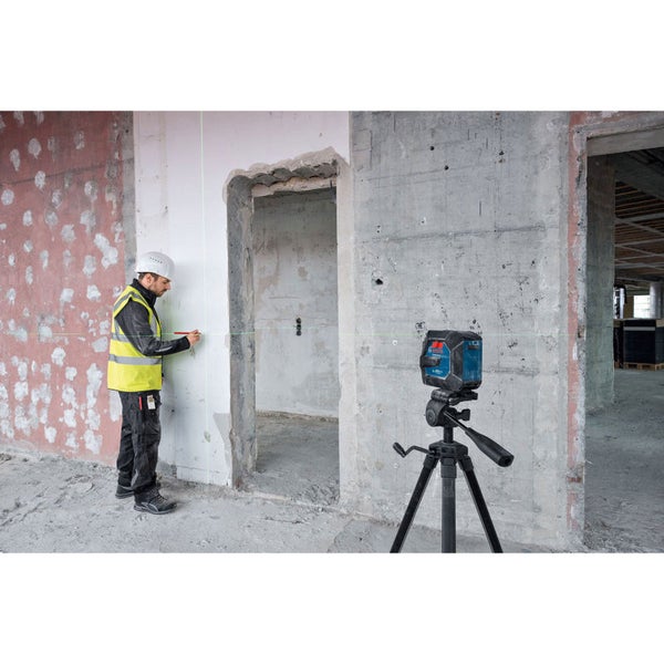 Ein Arbeiter benutzt einen Linienlaser von Bosch auf einem Stativ zur Ausrichtung an einer Wand auf einer Baustelle.