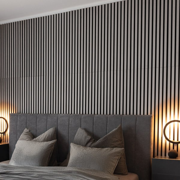 Schlafzimmer mit vertikalen Akustikpaneelen aus Holz an der Wand hinter einem gepolsterten Bett, moderner Stil und gemütliche Beleuchtung.