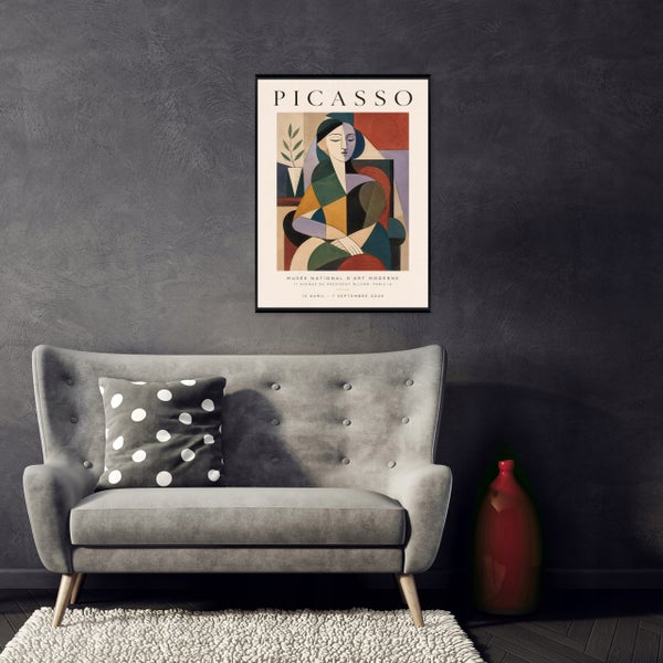 Wohnzimmer mit Picasso Kunstplakat in schwarzem Rahmen über einem gepolsterten Sofa mit getupftem Kissen und einer Bodenvase.