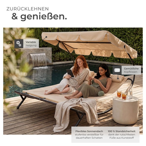 Beige Doppel-Sonnenliege aus Metall mit verstellbarem Sonnendach und Kissen, genutzt von zwei Frauen auf einer hellen Holzterrasse am Pool.