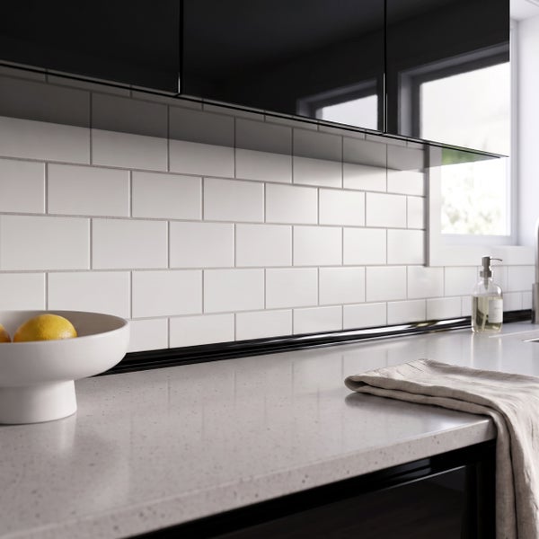 Moderne Küche mit Fliesenrückwand, heller Arbeitsplatte, Oberschränken und Obstschale auf der Anrichte.