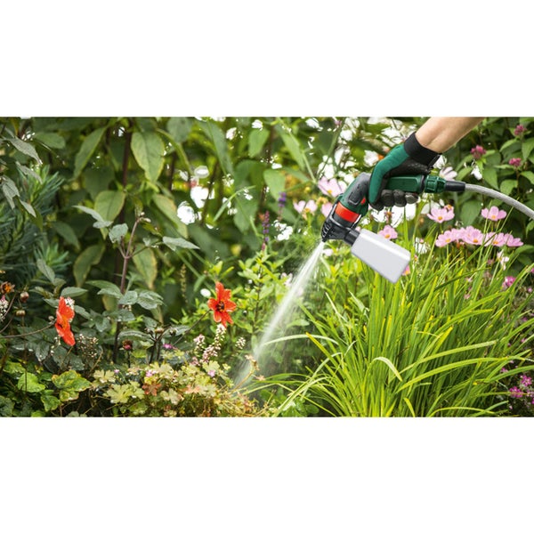 Gartenszene mit einer Person, die mit einer Gartenspritze Pflanzen bewässert