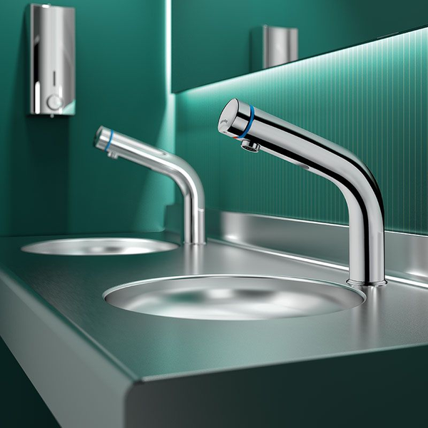 Moderne Infrarot-Waschtischarmatur aus Chrom auf einem Edelstahl-Waschtisch in einem hellen, organisierten Badezimmer.
