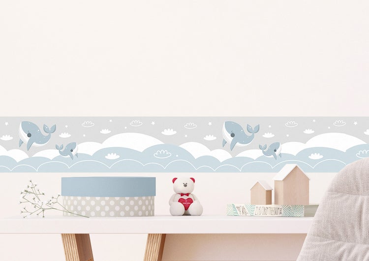 Selbstklebende Wandbordüre mit Wal- und Wolkenmotiven in einem hellen Kinderzimmer über einem Schreibtisch.