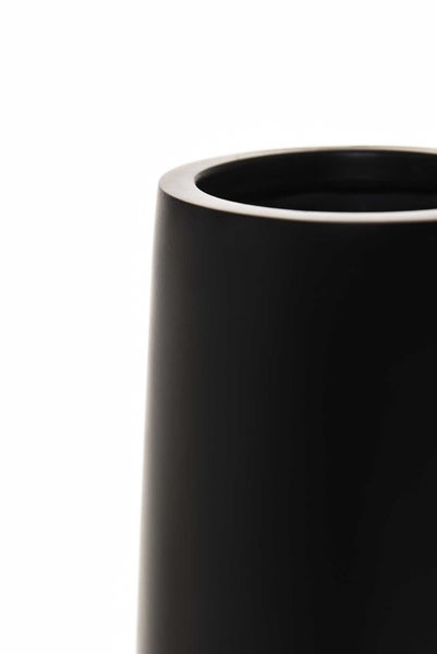 Hohe schwarze Bodenvase mit dekorativen weißen Zweigen und dunklen Dekokugeln auf Holzboden vor einer strukturierten Wand.