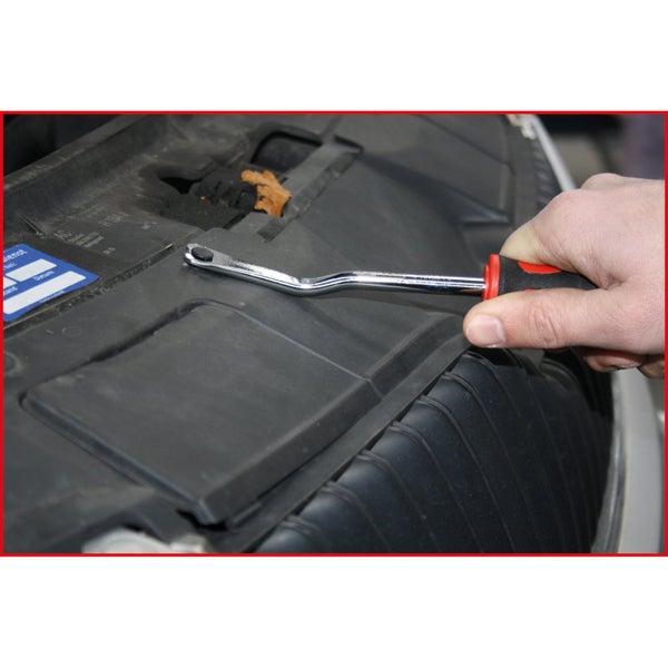 Person entfernt eine Kunststoffabdeckung mit einem Polsterentferner aus einem Motorraum.