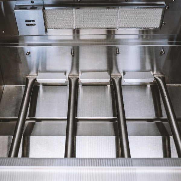 Innenansicht eines Gasgrills aus Edelstahl mit vier Hauptbrennern und einem Infrarot-Keramik-Rückbrenner.