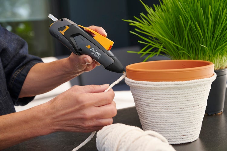 Dekorieren eines Blumentopfs mit einer Heißklebepistole und einer Kordel