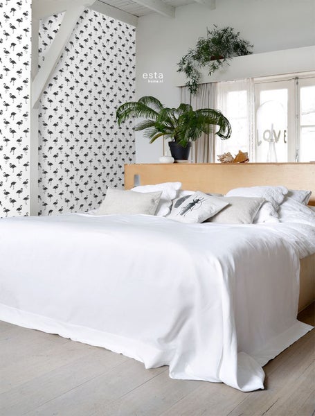 Schlafzimmer mit Bett, Nachttisch, Zimmerpflanzen und Tapete mit Flamingomuster