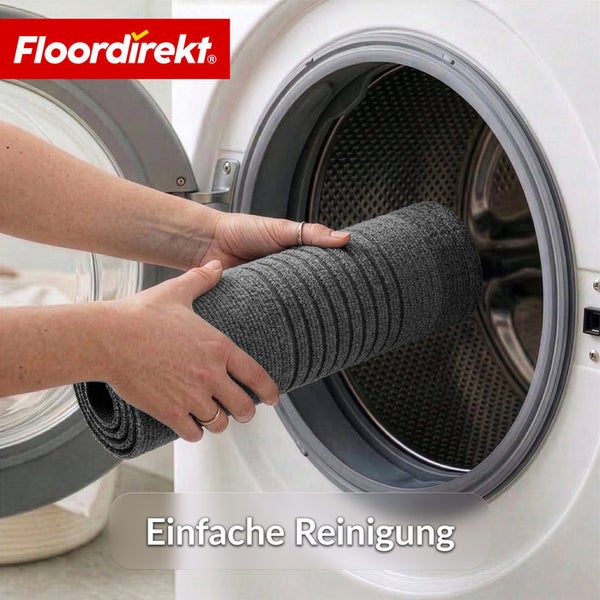 Floordirekt Logo. Eine Person legt eine zusammengerollte graue Matte in eine Waschmaschine zur einfachen Reinigung.
