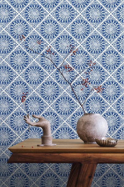 Gemusterte Tapete mit Blumenornamenten und Dekorationsgegenständen auf einem Holztisch