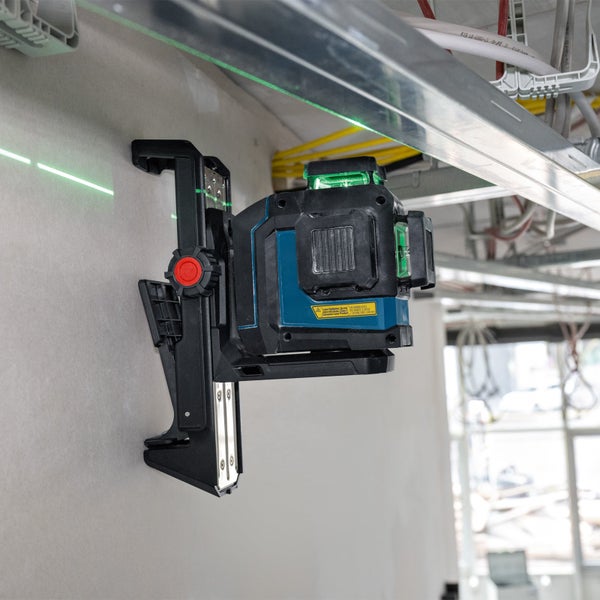 Kreuzlinienlaser mit grüner Laserlinie an Wandhalterung montiert im Innenausbau bei der Montage einer Unterkonstruktion.