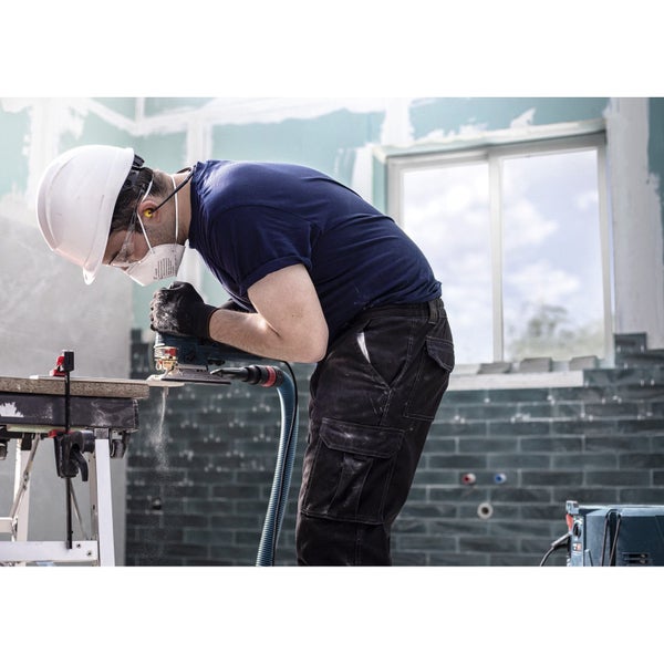 Handwerker schleift Holz mit einem Schleifgerät. Er trägt Schutzkleidung.