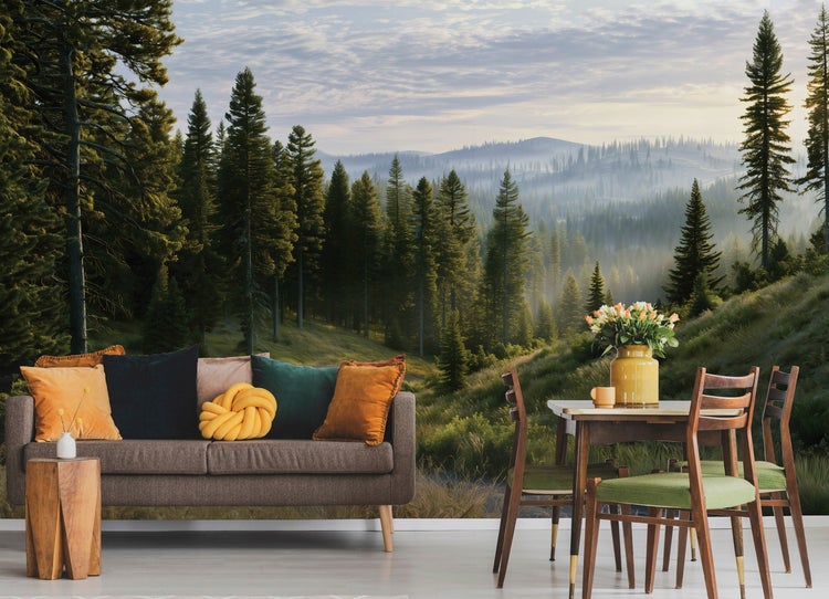 Fototapete mit Bergwaldmotiv hinter einem Sofa und einem Esstisch mit Stühlen in einem modern eingerichteten Wohnbereich.