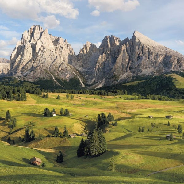 Landschaft mit Bergen, Wiesen und kleinen Häusern