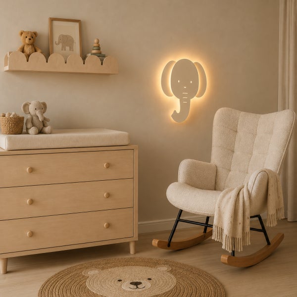 Helles Kinderzimmer mit Holzkommode, Schaukelstuhl und einer Wandleuchte in Elefantenform mit sanfter Beleuchtung.