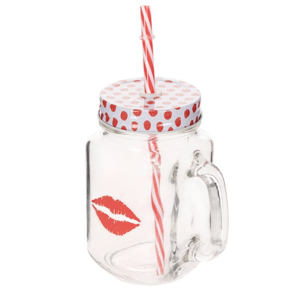 Trinkbecher aus Glas mit Henkel, Deckel und Strohhalm, Lippen-Motiv, auf Holztisch in heller Küche neben Erdbeerschale und Glaskaraffe.