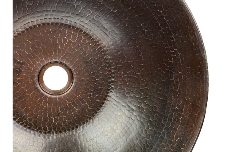 Nahaufnahme eines Waschbeckens aus gehämmertem Metall mit Abflussloch