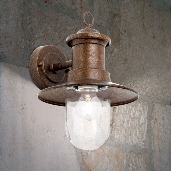 Rustikale Außenwandleuchte in Bronze-Optik mit klarem Glas und breitem Schirm, montiert an einer Steinwand.