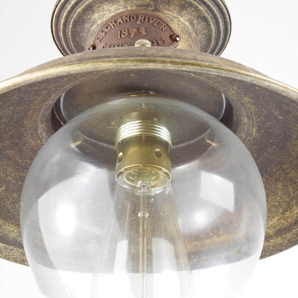 Detailaufnahme einer Deckenleuchte mit einem klaren Glasschirm und einem Lampenschirm aus Metall