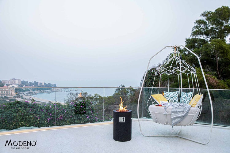 Modeno Gas-Feuerstelle auf einer Terrasse mit weißem Hängesessel und Meerblick.