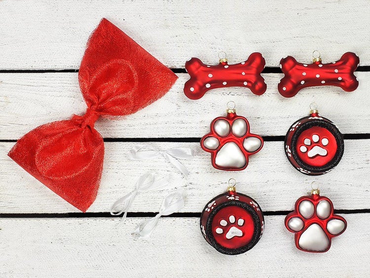 Weihnachtsbaumschmuck Set mit Pfoten und Knochen Motiven inklusive einer großen Schleife und Aufhängern auf einer Holzoberfläche.