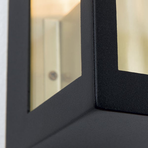 Detailansicht einer modernen Wandleuchte mit schwarzem, strukturiertem Metallrahmen und Glaseinsätzen.