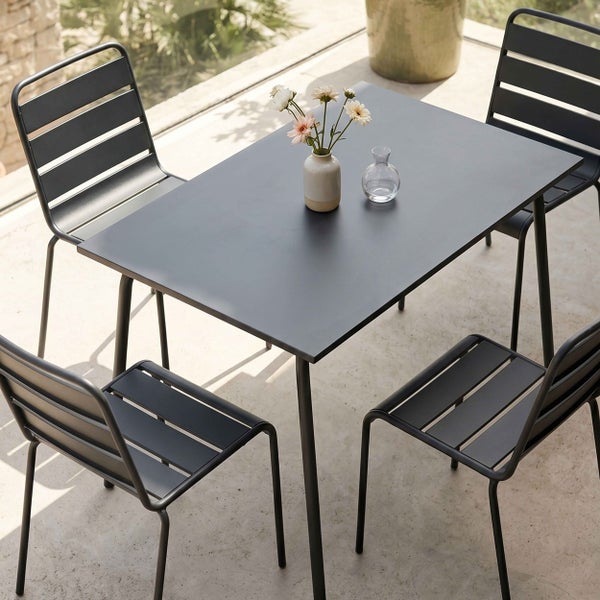 Moderne Gartenmöbel-Sitzgruppe mit einem rechteckigen Metalltisch und vier Lamellenstühlen auf einer hellen Terrasse.