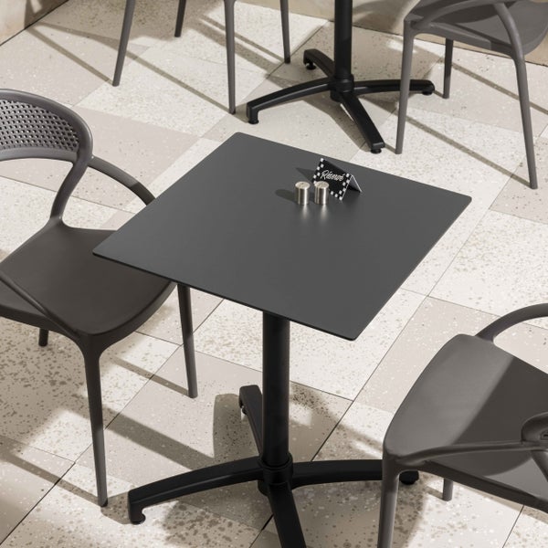 Anthrazitfarbener, quadratischer Bistrotisch mit Mittelfuß und passenden Armlehnenstühlen auf einer hellen, organisierten Terrasse.