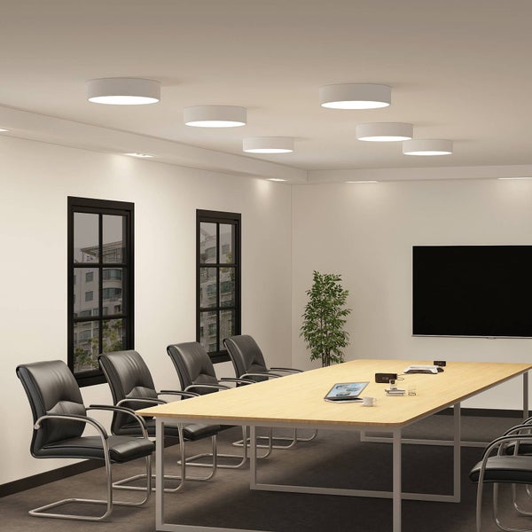 Moderne LED Deckenleuchten in einem hellen Konferenzraum mit großem Holztisch und schwarzen Lederstühlen.