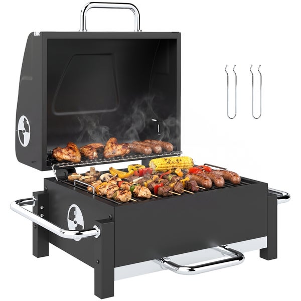 Tragbarer schwarzer Holzkohlegrill mit offenem Deckel, belegt mit Hähnchenflügeln, Würstchen, Mais und Spießen. Inklusive zwei Rosthebern.