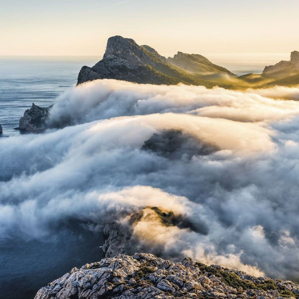 Berge ragen aus einer Wolkendecke über dem Meer