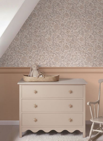 Schlafzimmer mit floral gemusterter Tapete, rustikalem Holznachttisch und Bett mit gesteppter Decke.