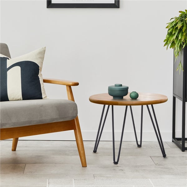 Runder Beistelltisch aus Holz mit Metallbeinen neben einem Sessel.