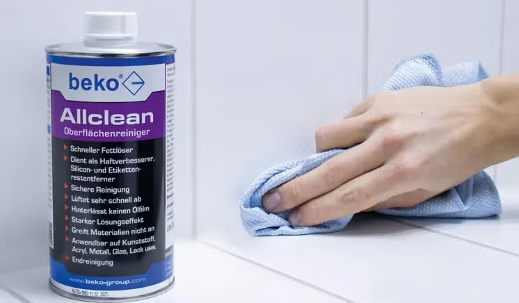 Beko Allclean Oberflächenreiniger in einer Flasche neben einer Hand, die eine Oberfläche mit einem Tuch reinigt.