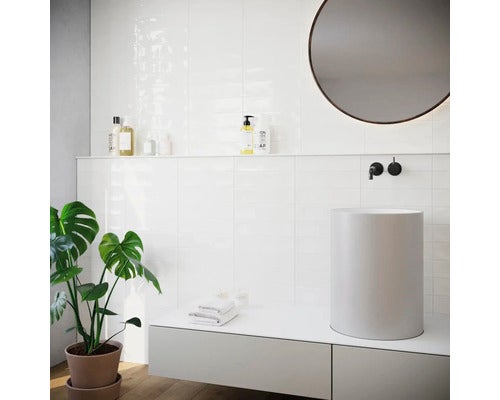 Helles Badezimmer mit weißen Fliesen, rundem Spiegel und Aufsatzwaschbecken.