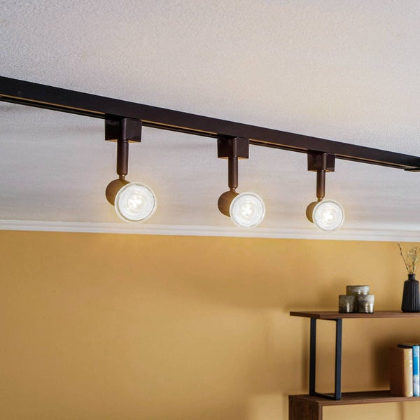Dreiflammiges Schienensystem mit verstellbaren Strahlern an der Decke montiert, Raum mit gelber Wand und Holzregal.